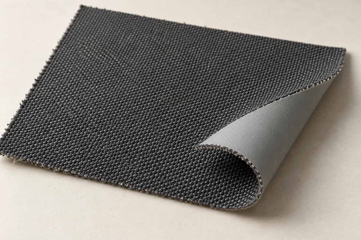 Charcoal woven fabric sample with a corner folded back to show its smooth light-gray reverse